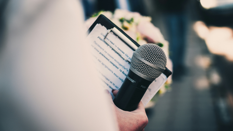 A photo showing a person speaking at the front of an audience.