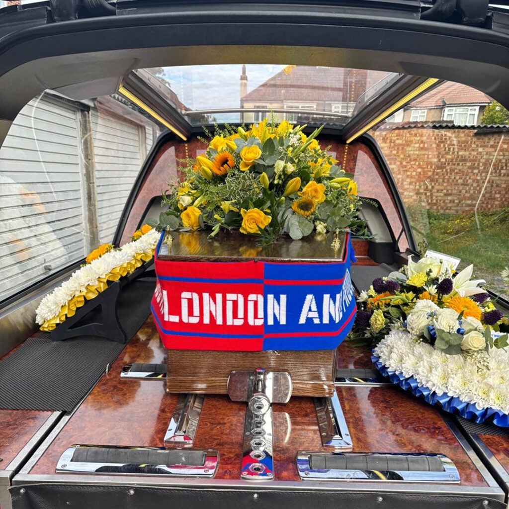 A phot of a personalised coffin positioned into the rear of a hearse.