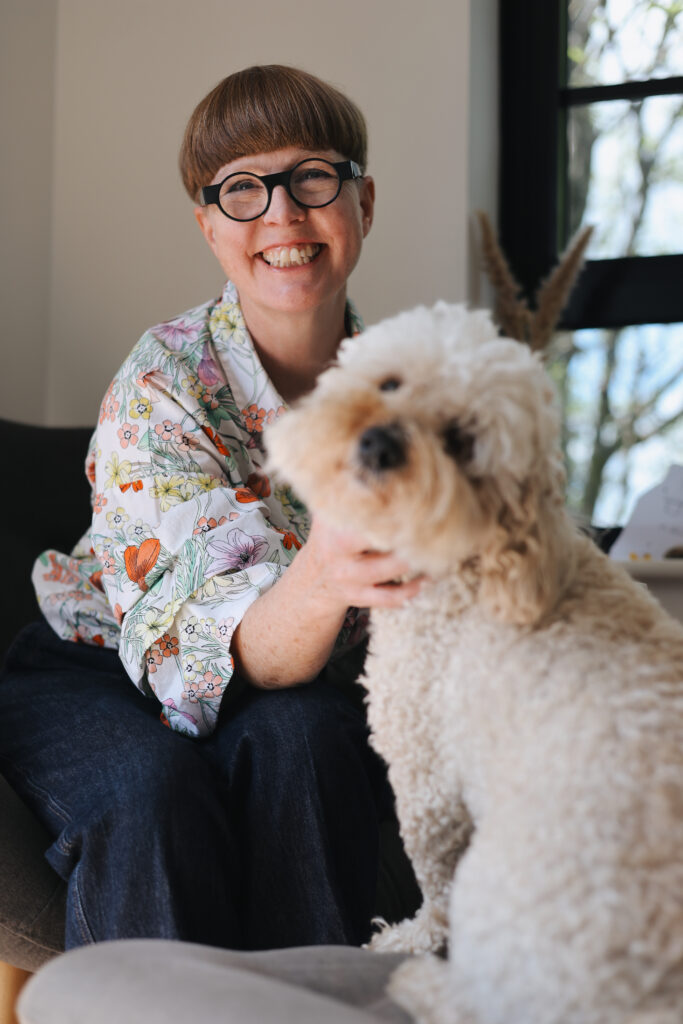 Beth MacLeod, independent funeral celebrant, smiling at home with her dog.